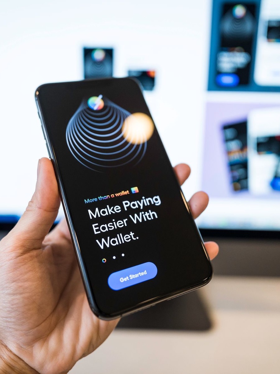 Hand holding a phone showing a fintech wallet app onboarding screen