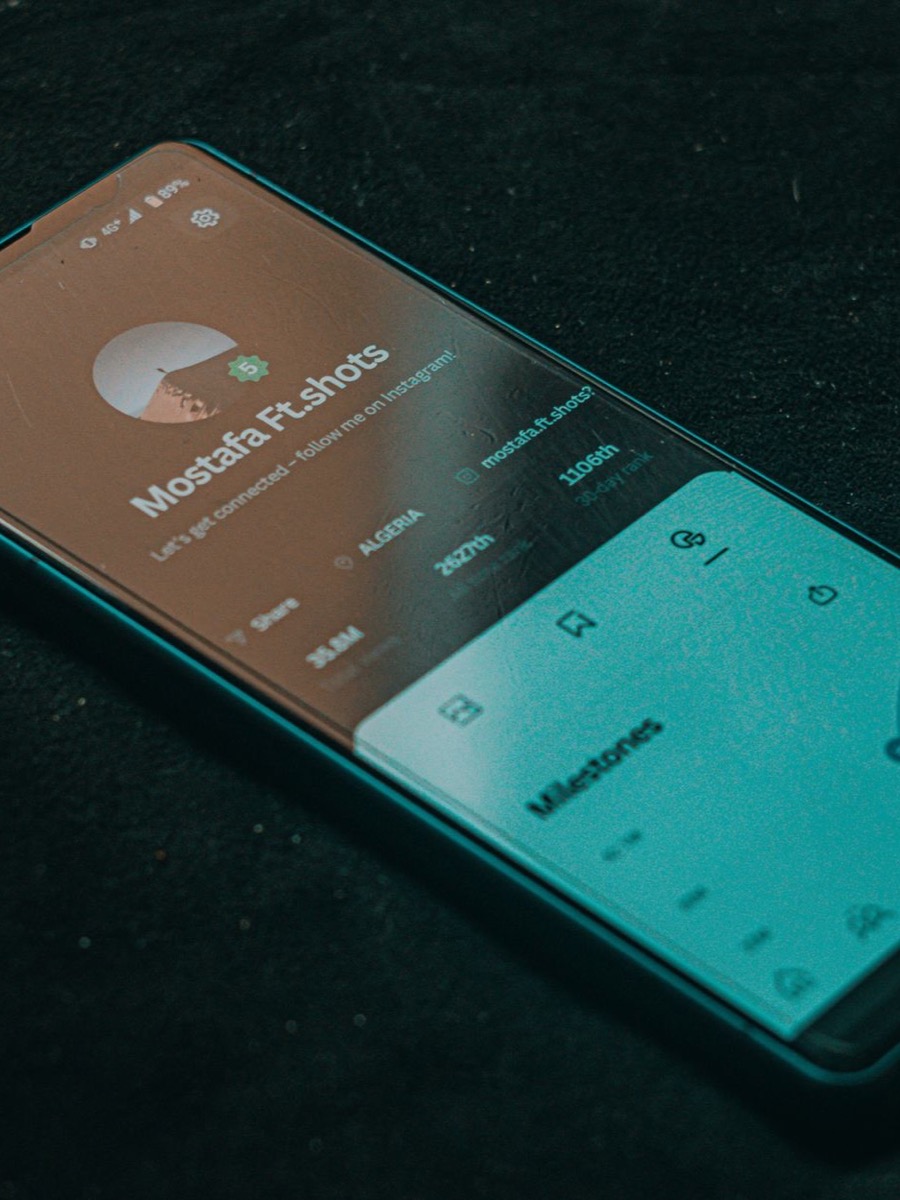 Smartphone with a dark teal app interface on a dark surface